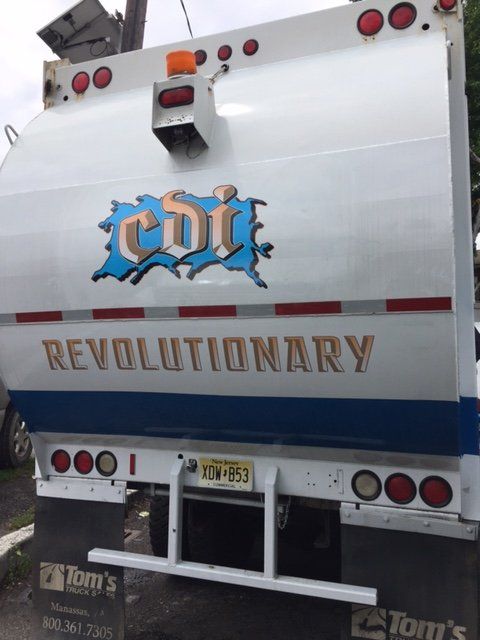 A trash truck that says revolutionary on the back