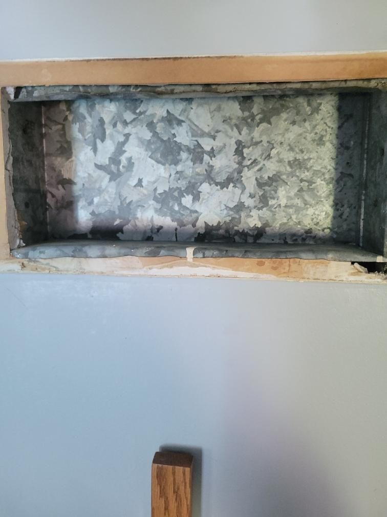 Empty recessed wall niche with peeling gray paint above a wooden post against a white wall