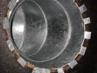 Close-up of a circular metal pipe with a toothed edge and a dark interior.