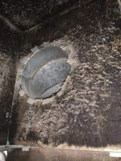 Close-up of a dusty wall vent with a circular metal cover and dark soot stains