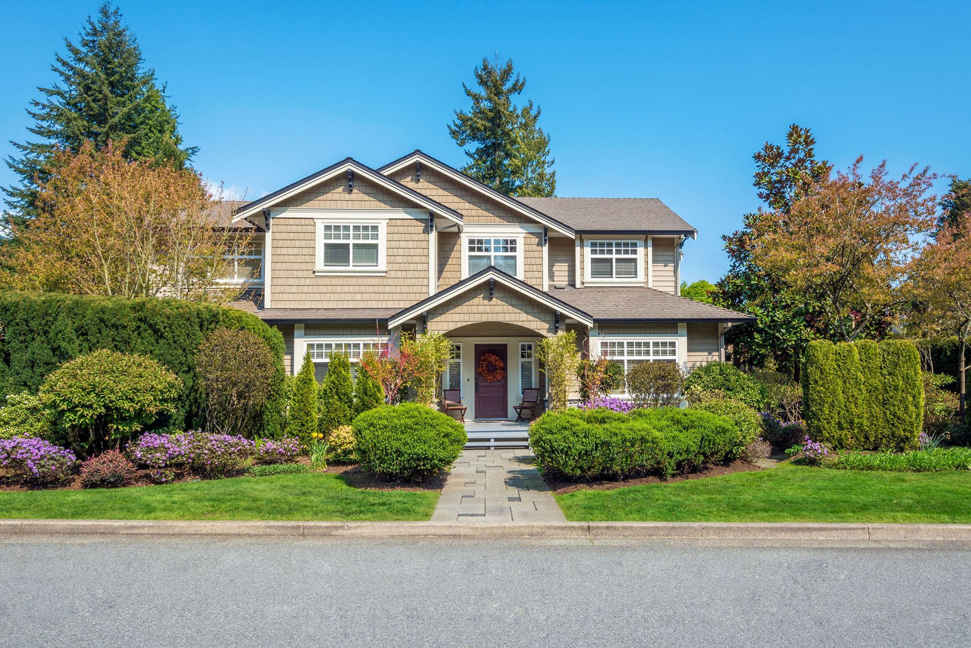 A large house with a lush green lawn and bushes in front of it