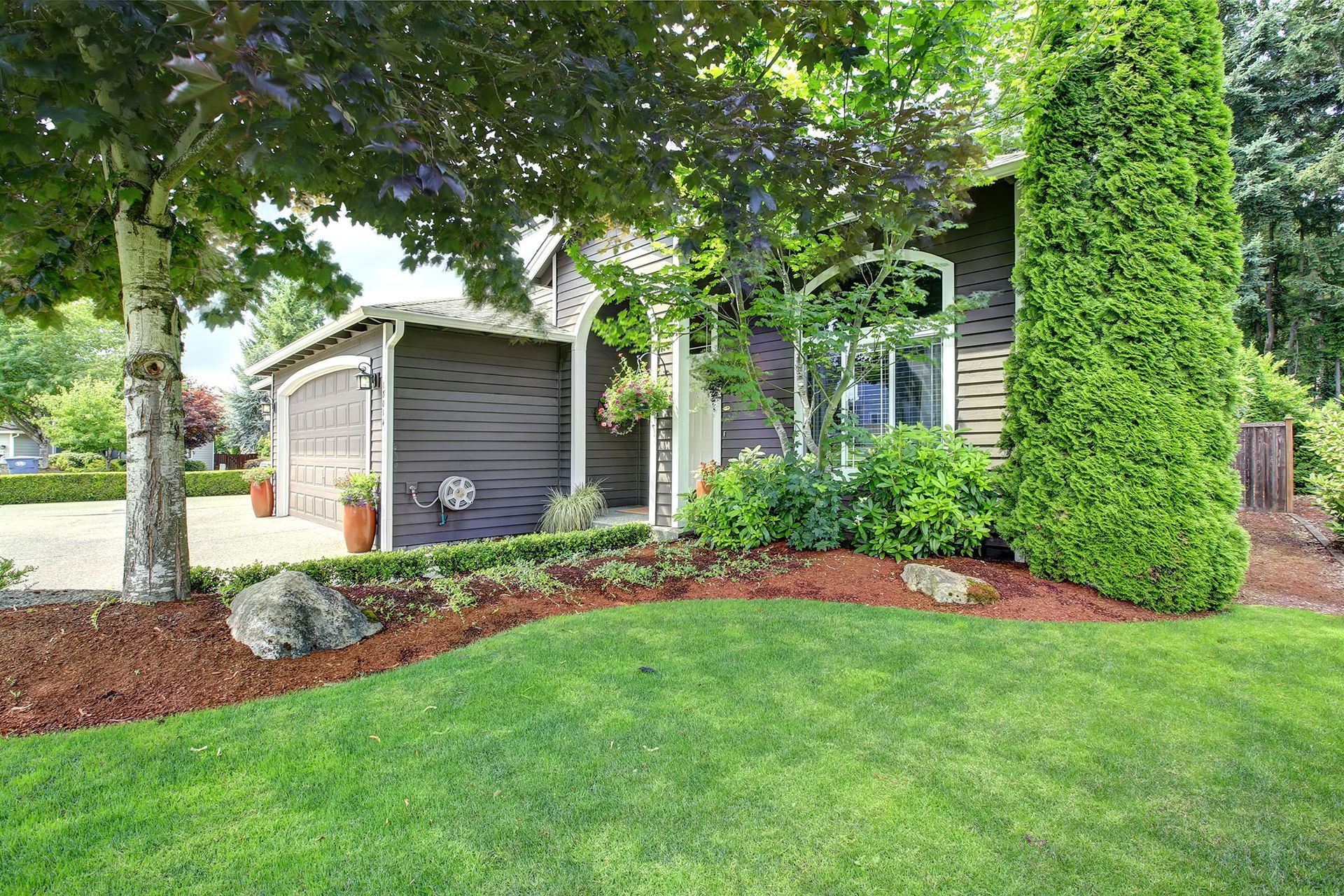 A house with a lush green lawn and trees in front of it