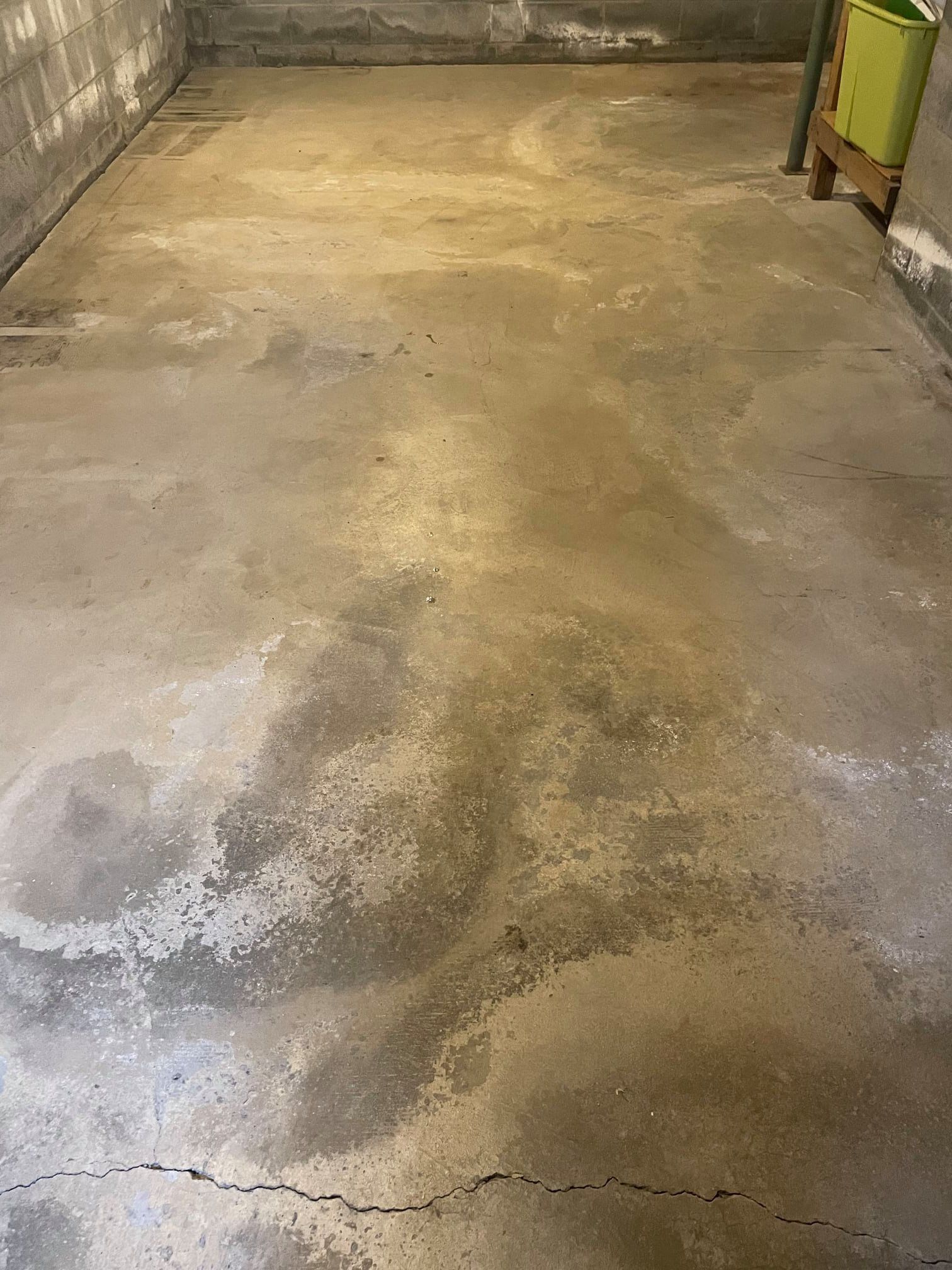 a concrete floor in a basement with a few spots of water on it .