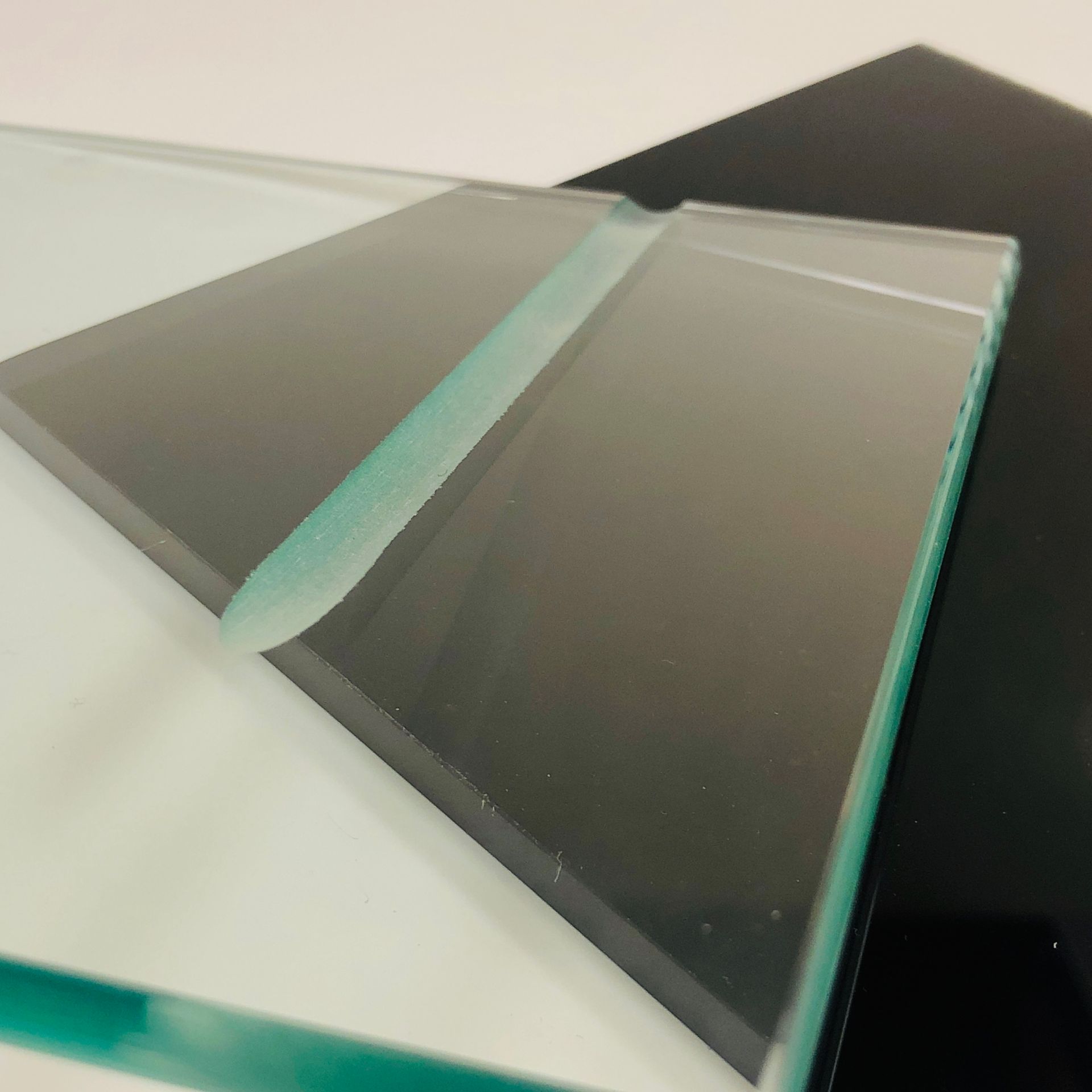 A close-up view of clear, thick glass panels showing beveled edges, with a deep groove between two pieces.
