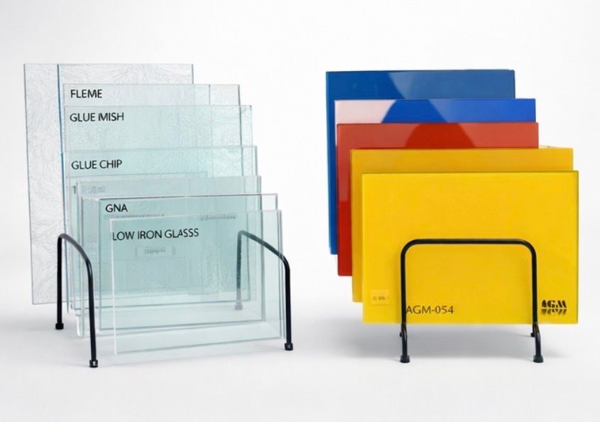 Two wire racks displaying various samples of clear glass and opaque, brightly colored flat panels on a white background.