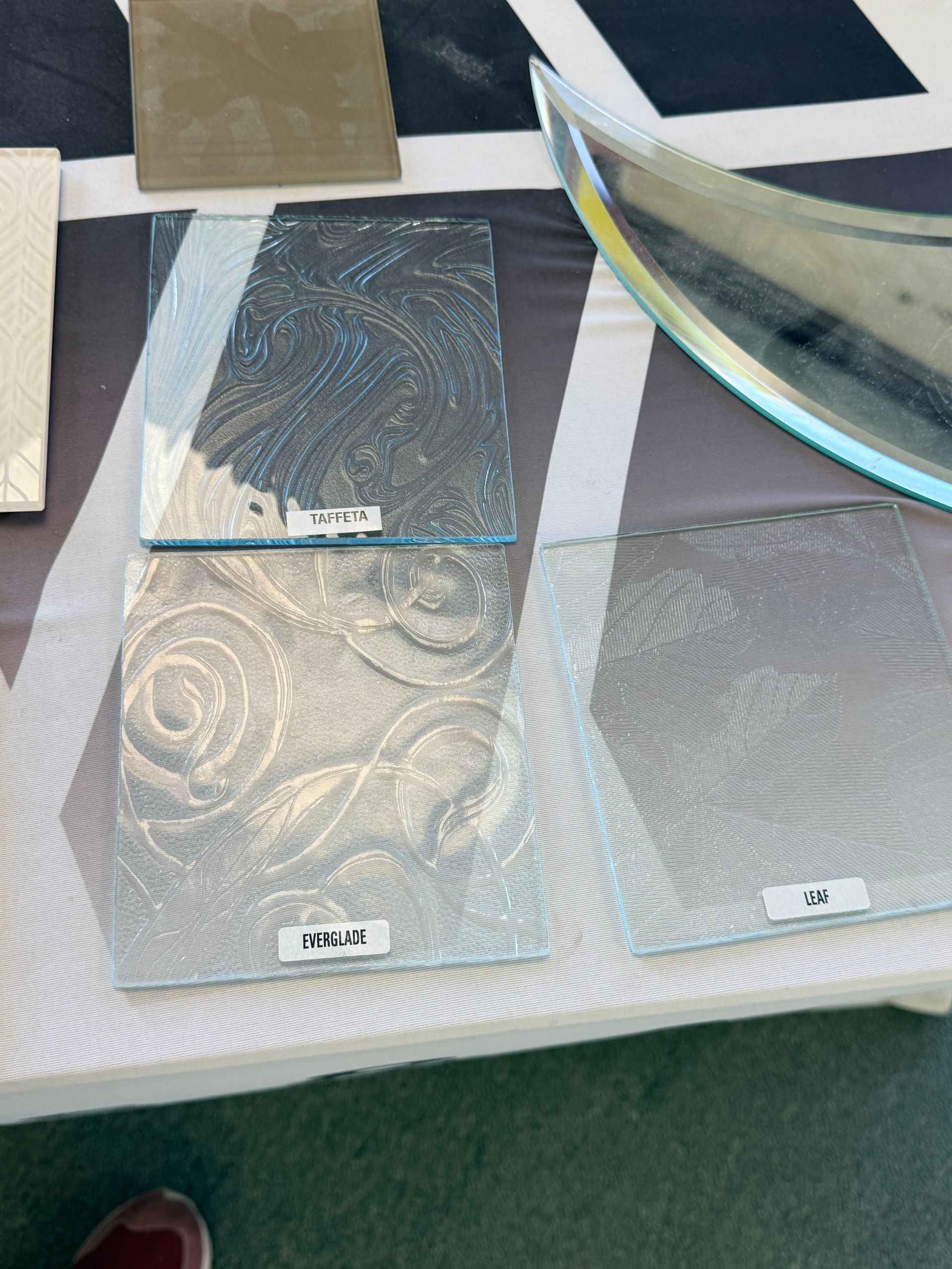 Several glass samples with different textures and patterns are displayed on a white table.