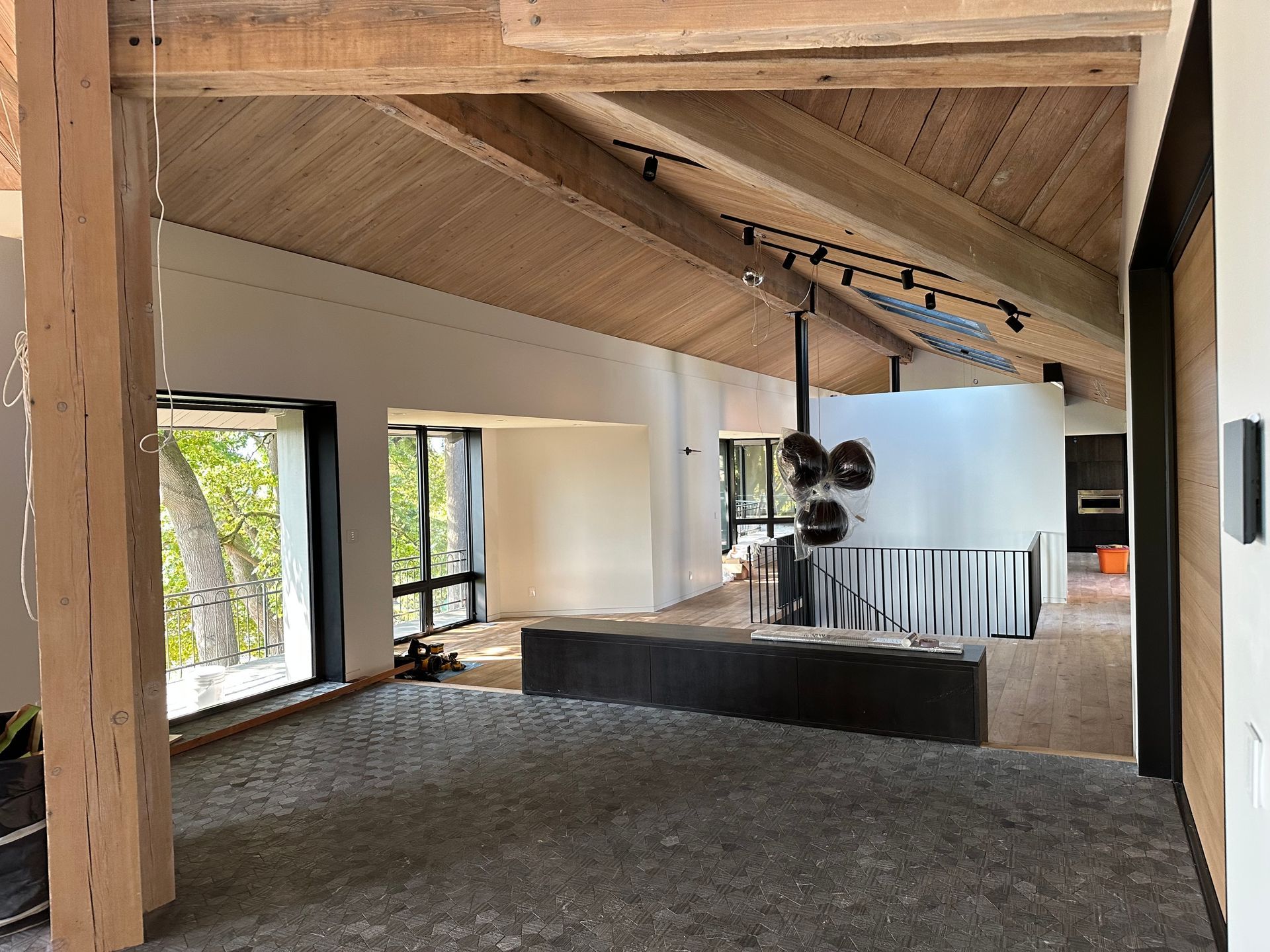 Open-plan modern interior with slanted wood ceiling, large windows, and a kitchen island.
