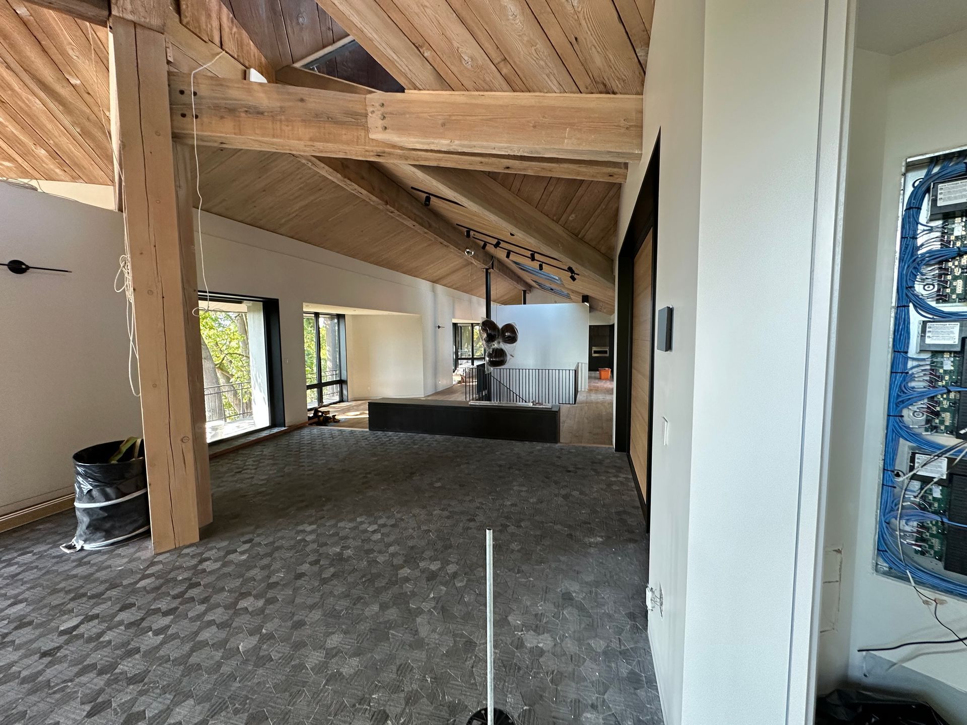 Empty vaulted room with exposed wood beams and unfinished walls, carpeted floor, and windows along one side
