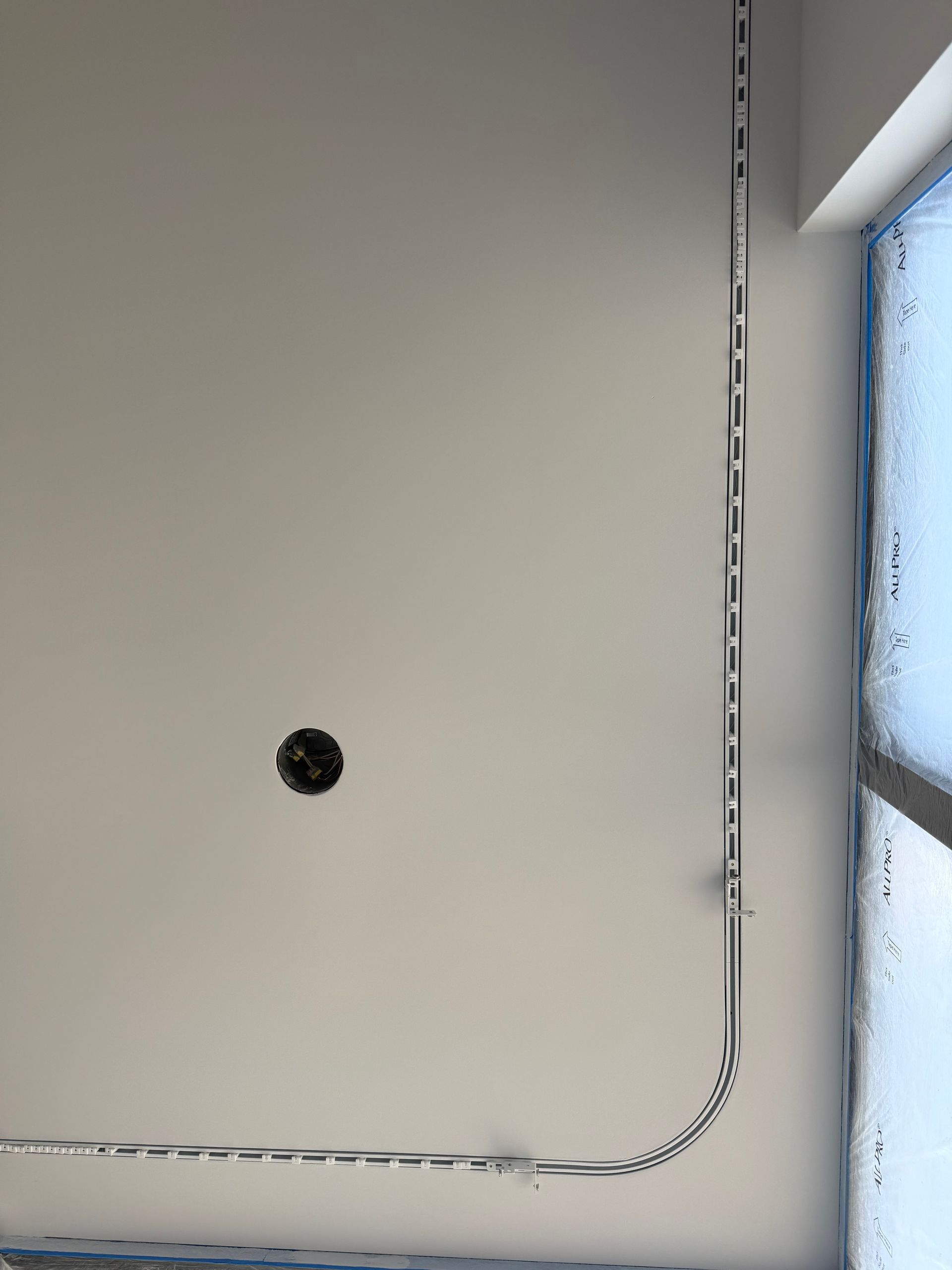 White ceiling corner with a small black hole and a window edge on the right.