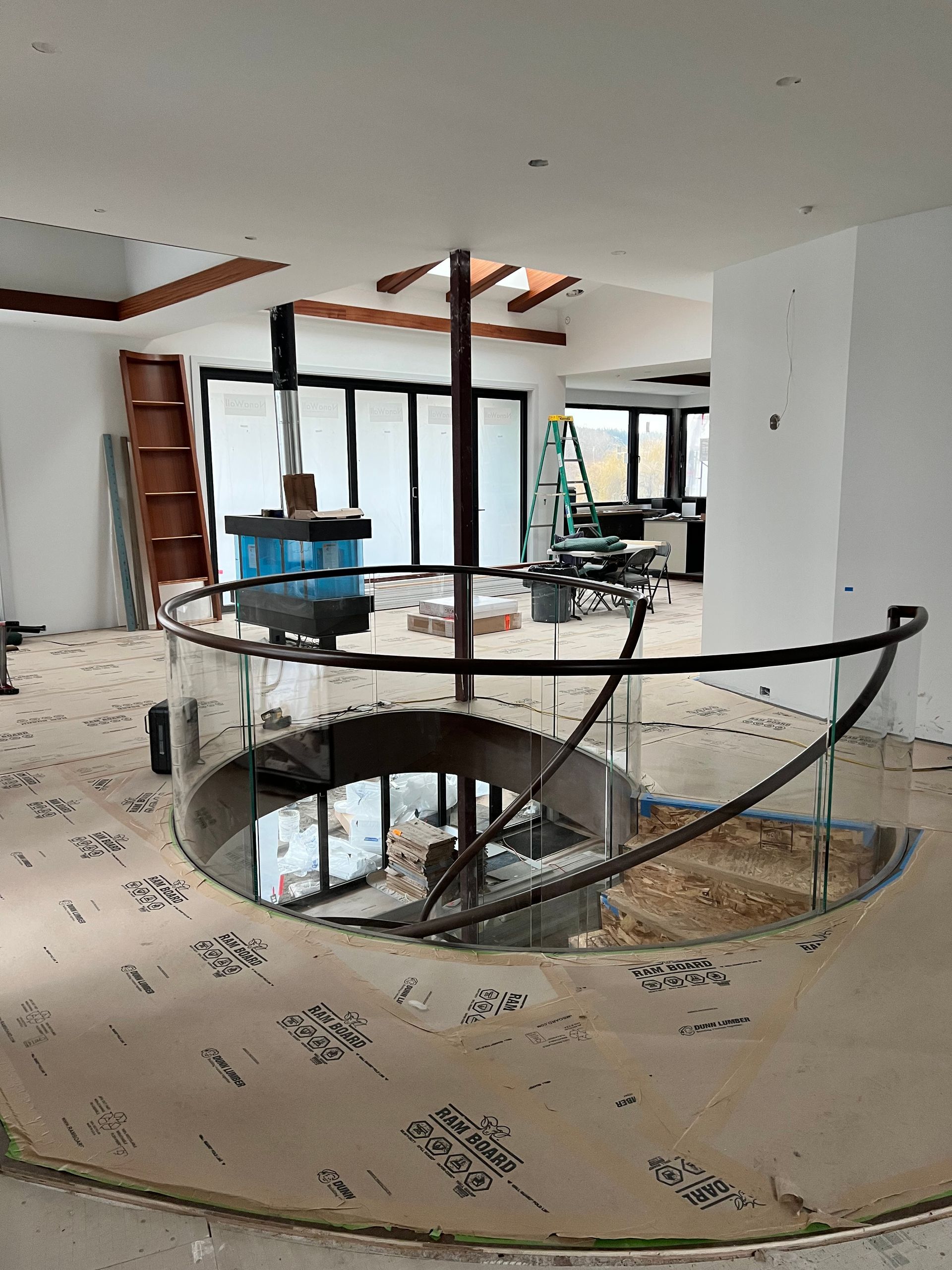 Interior of a home under renovation, with a stairwell opening and construction materials visible.
