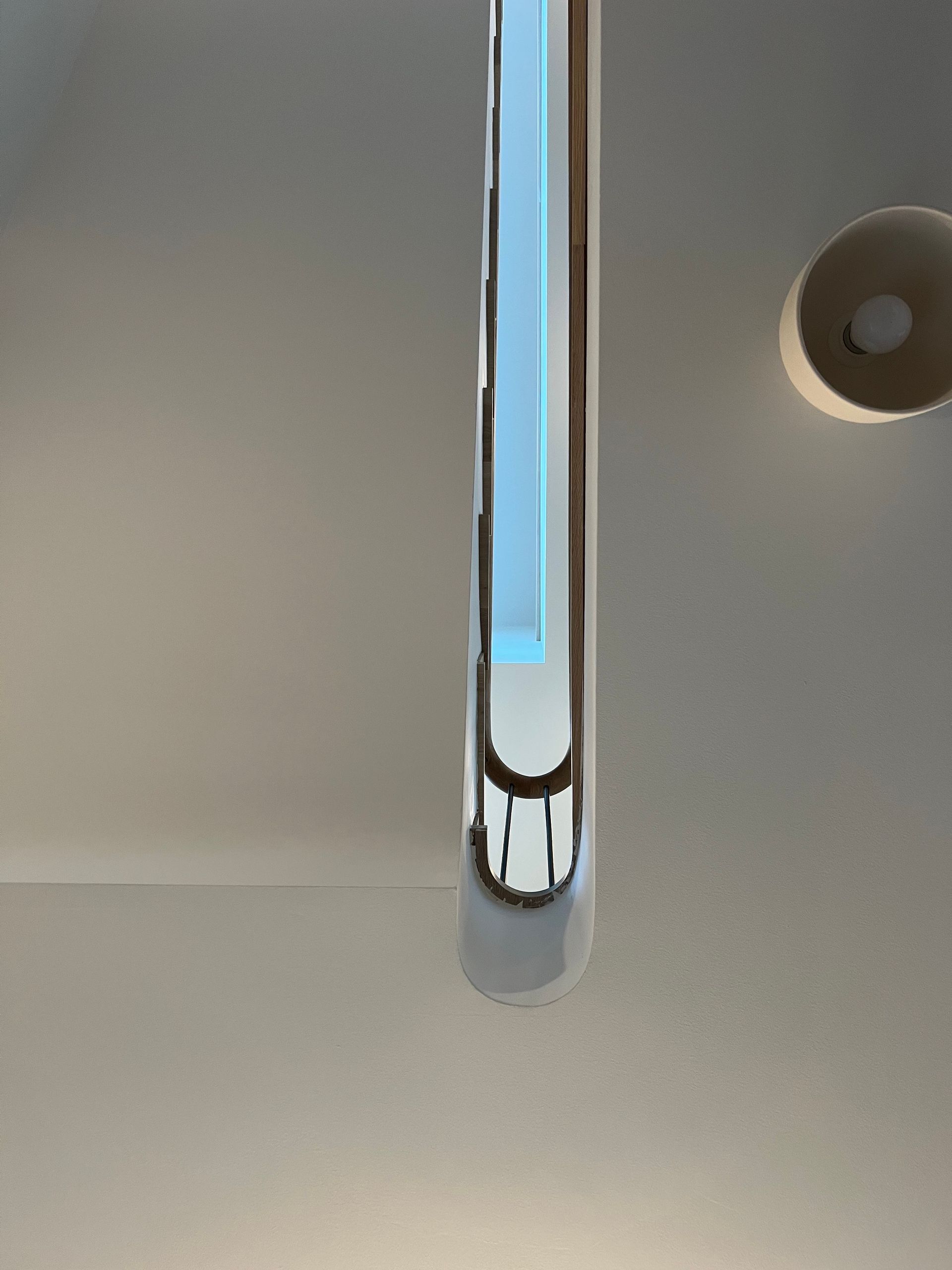 Ceiling-mounted elongated light fixture with a blue center panel against a white ceiling