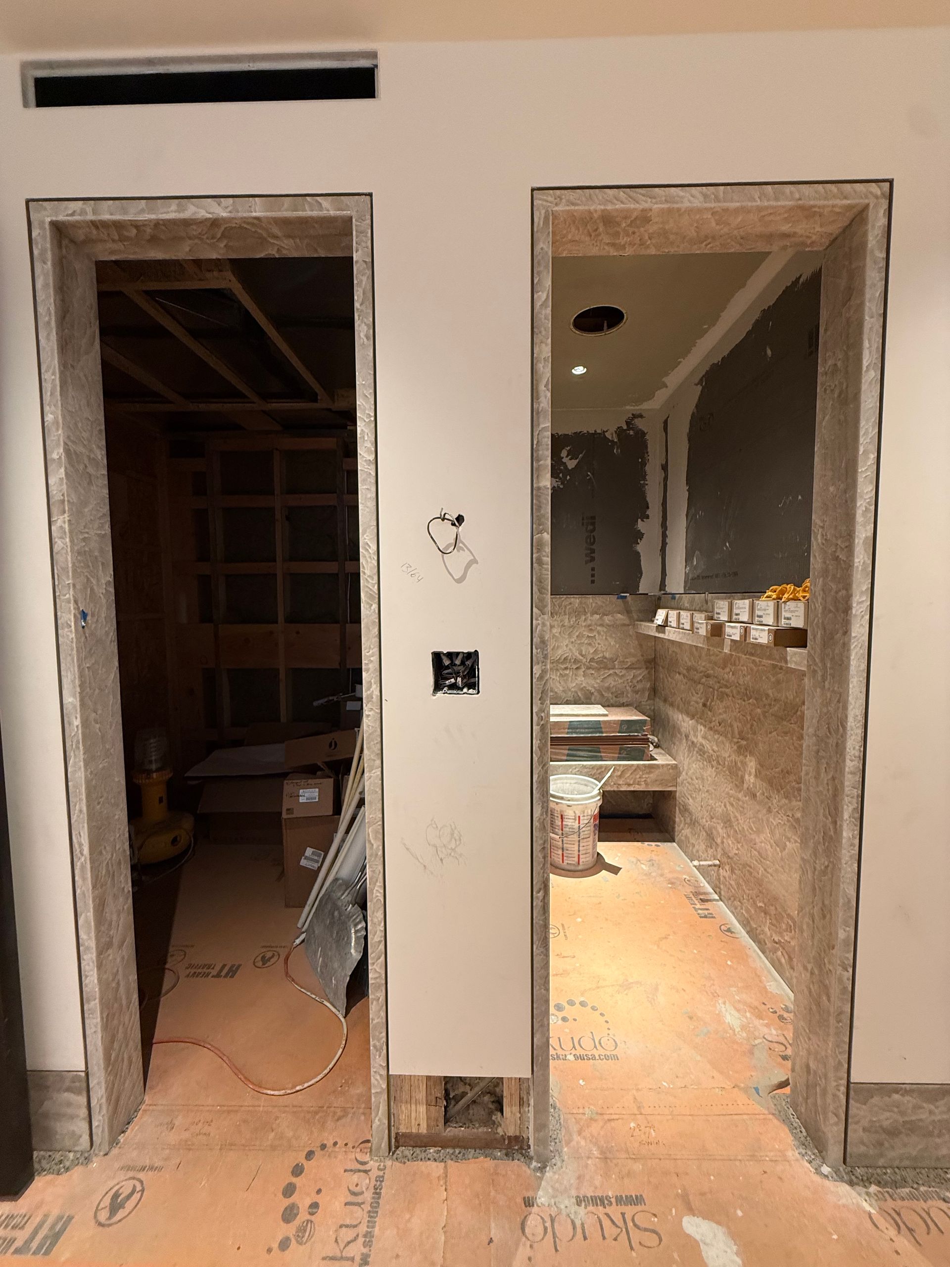 Two unfinished doorways in a renovated interior, with exposed walls and dusty floors.