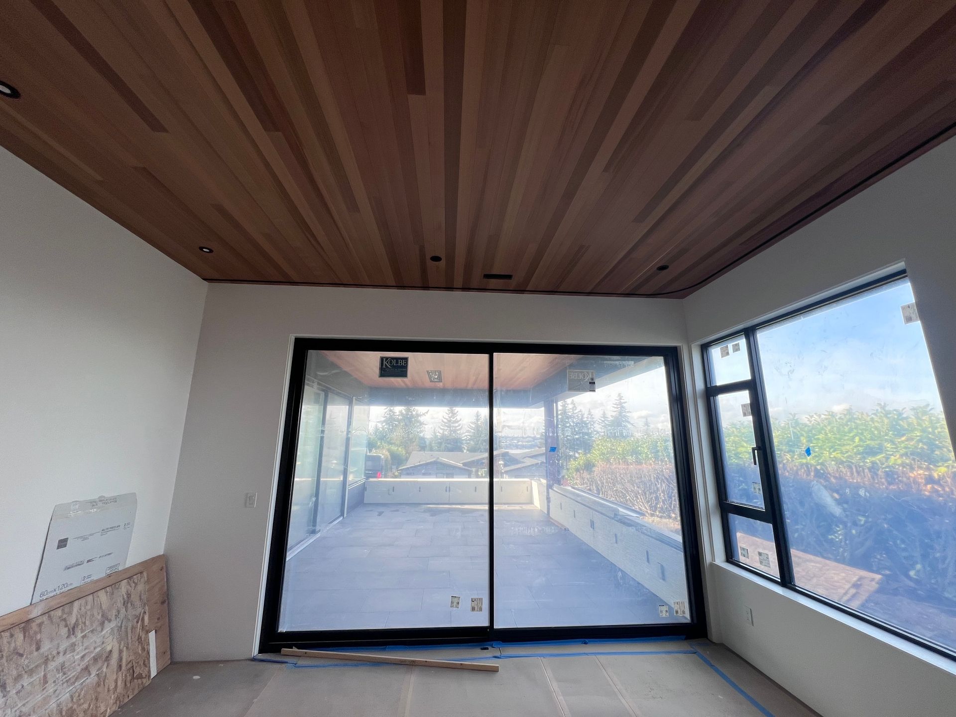 Modern interior with wood ceiling, white walls, and large sliding glass doors opening to a patio.