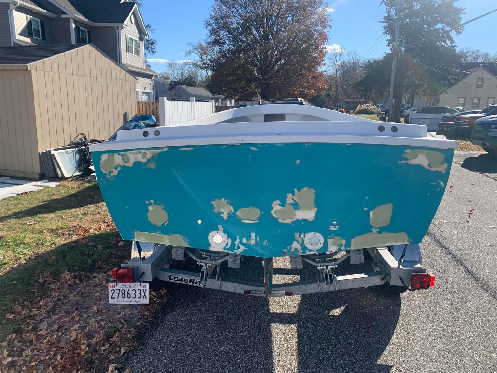 A blue and white boat is parked on the side of the road.
