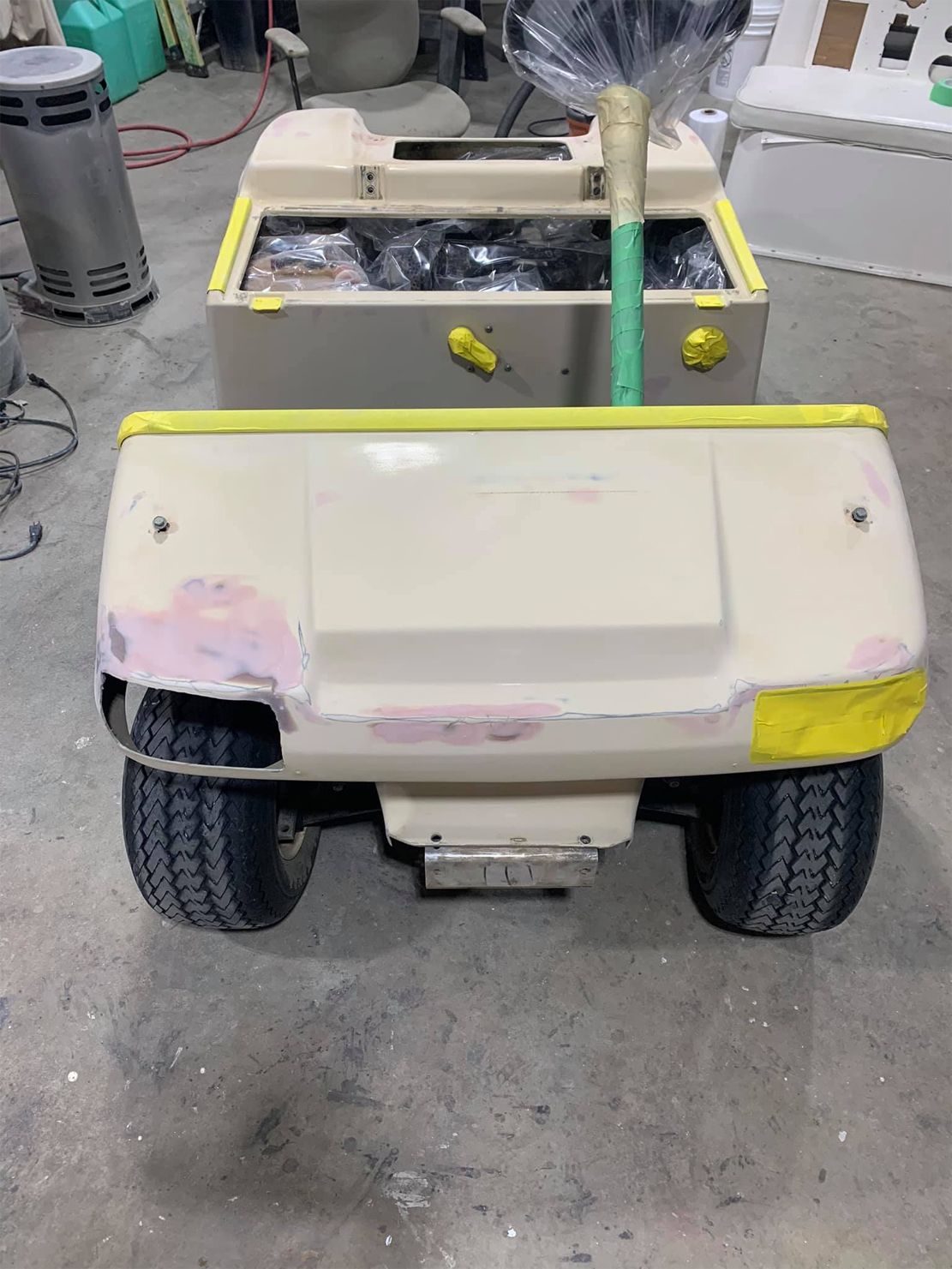 A golf cart is sitting on the ground in a garage.