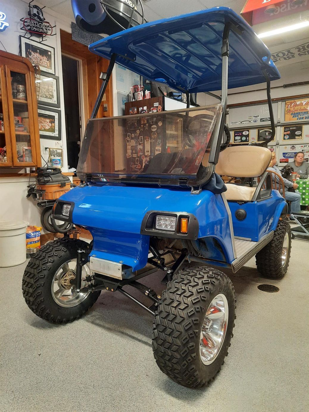 A blue golf cart is parked in a garage.
