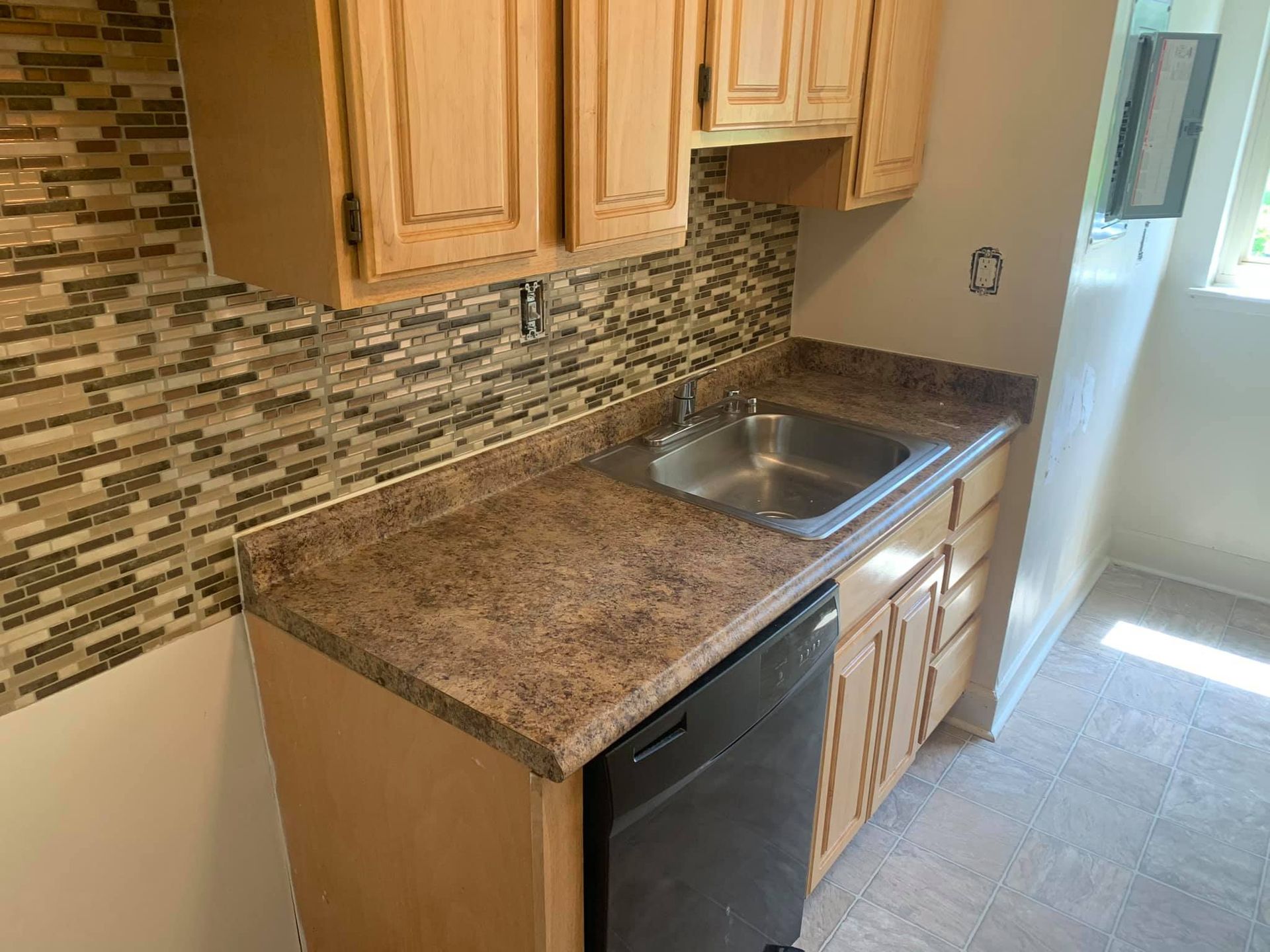 A kitchen with a sink, cabinets, and a dishwasher