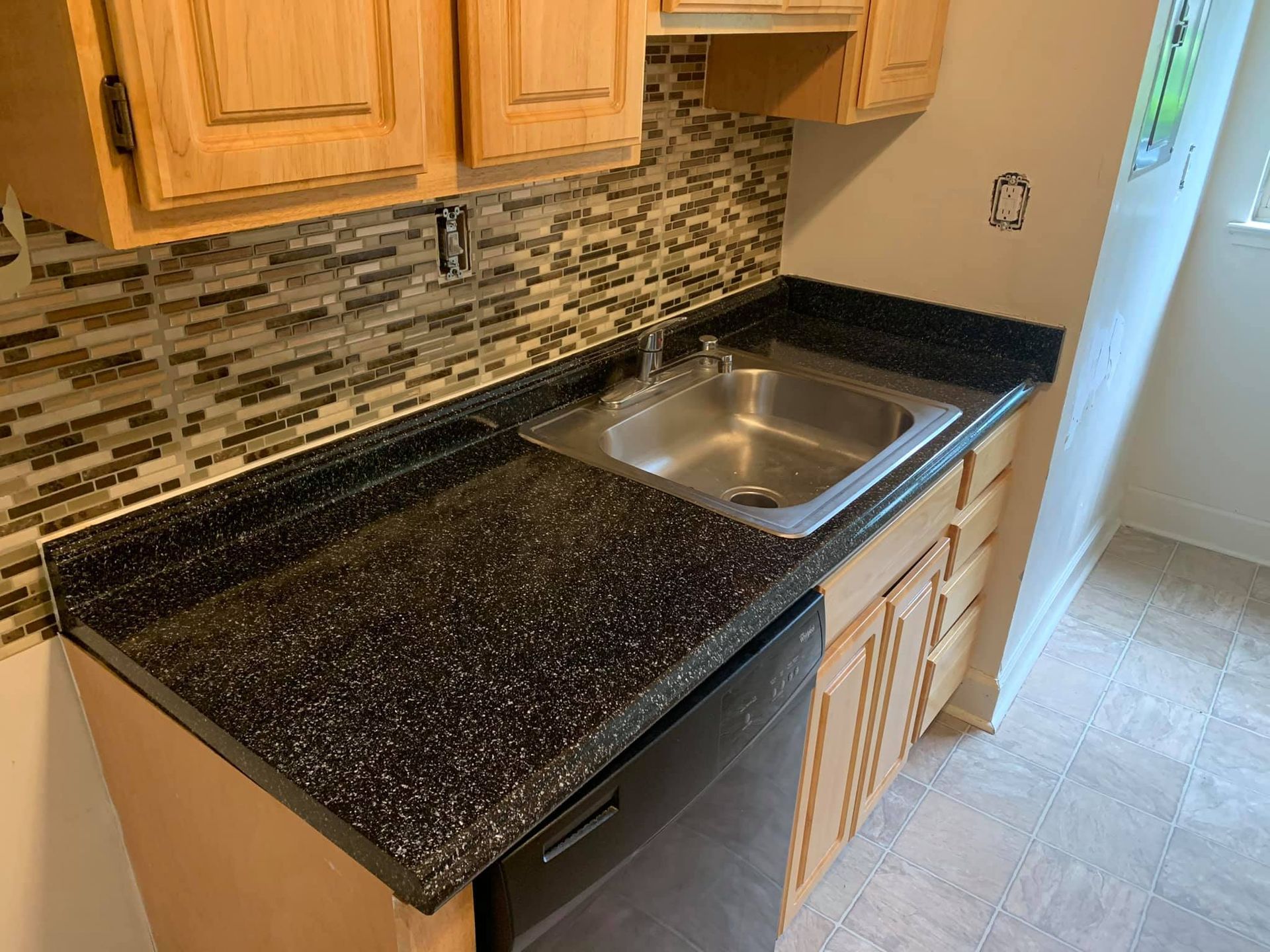 A kitchen with a sink, dishwasher, and cabinets
