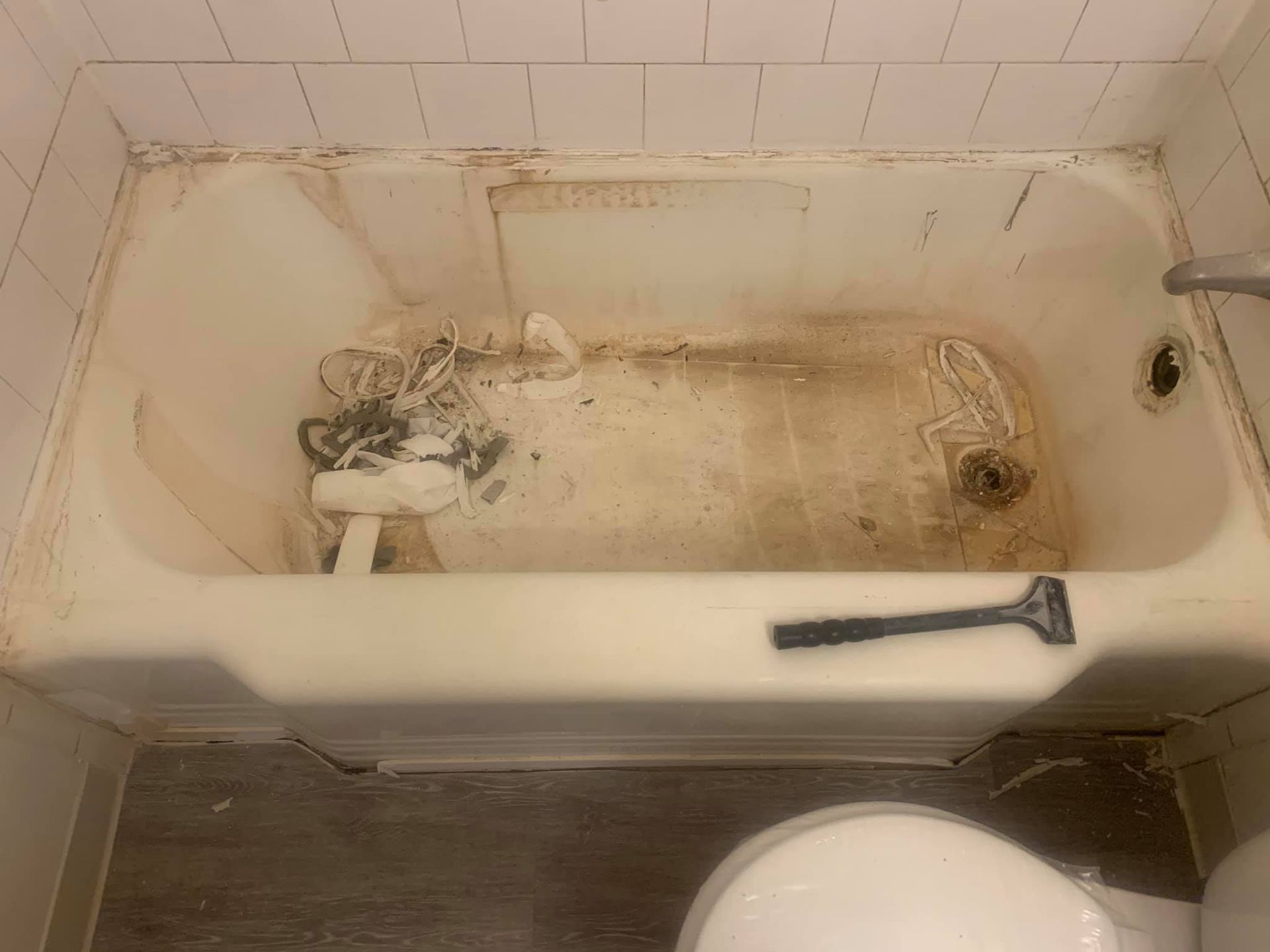 A dirty bathtub in a bathroom next to a toilet