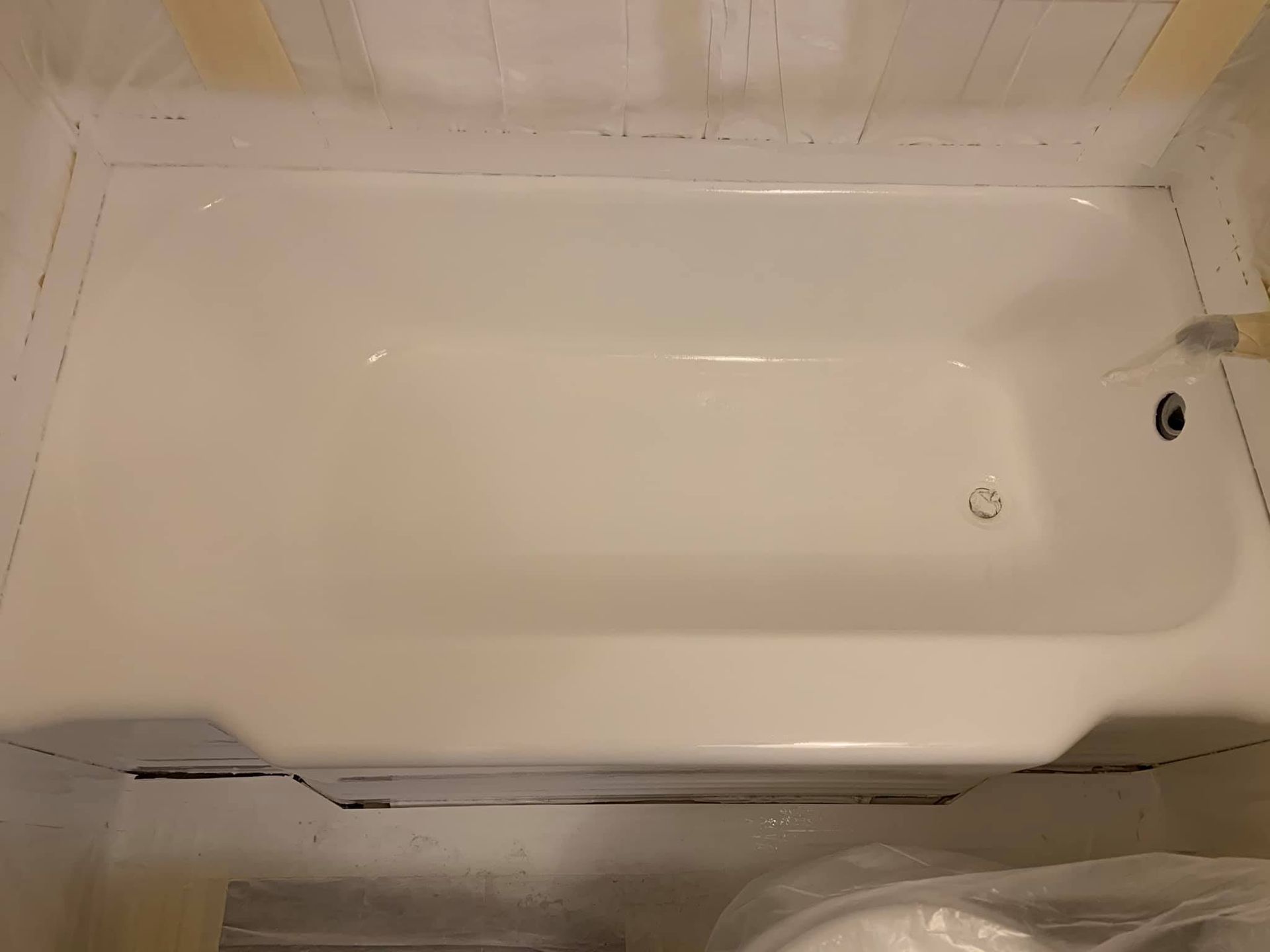 A white bathtub is being painted in a bathroom