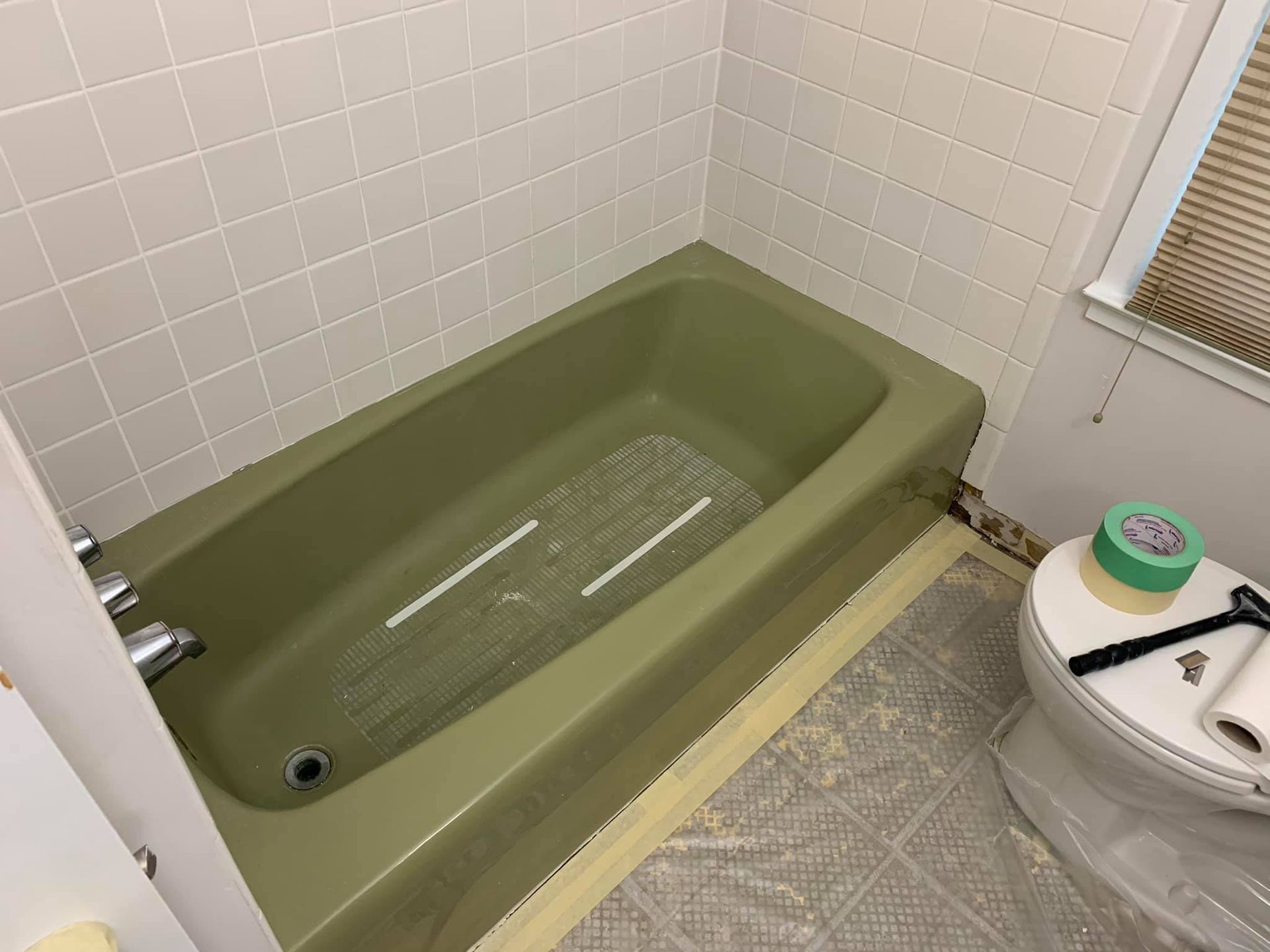 A bathroom with a green bathtub and a toilet