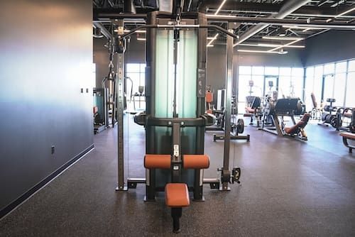 Gym interior with weight machines, treadmills, and exercise equipment under bright ceiling lights