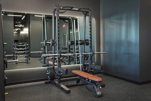 Modern gym with cable machine, bench, and mirrored wall in a dim room