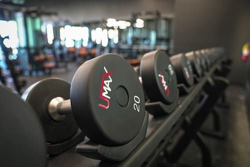 Row of black gym dumbbells on a rack, with a 20-pound UMAX weight in focus.