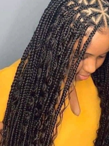Close-up of a person with long, box braids with water waves. The braids are black, some with a decorative pattern at the crown.