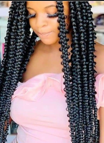 Woman with long, black butterfly braids wearing a pink off-the-shoulder top.