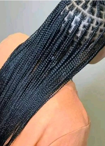 Box braids in black hair, close-up view from above, cascading down over an orange top.
