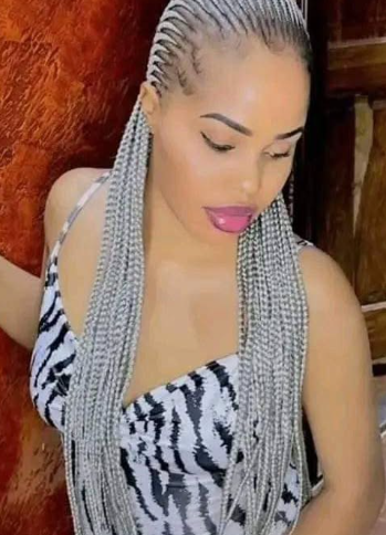 Woman with braided silver hair, wearing a zebra-print top, sticking out her tongue, indoors.