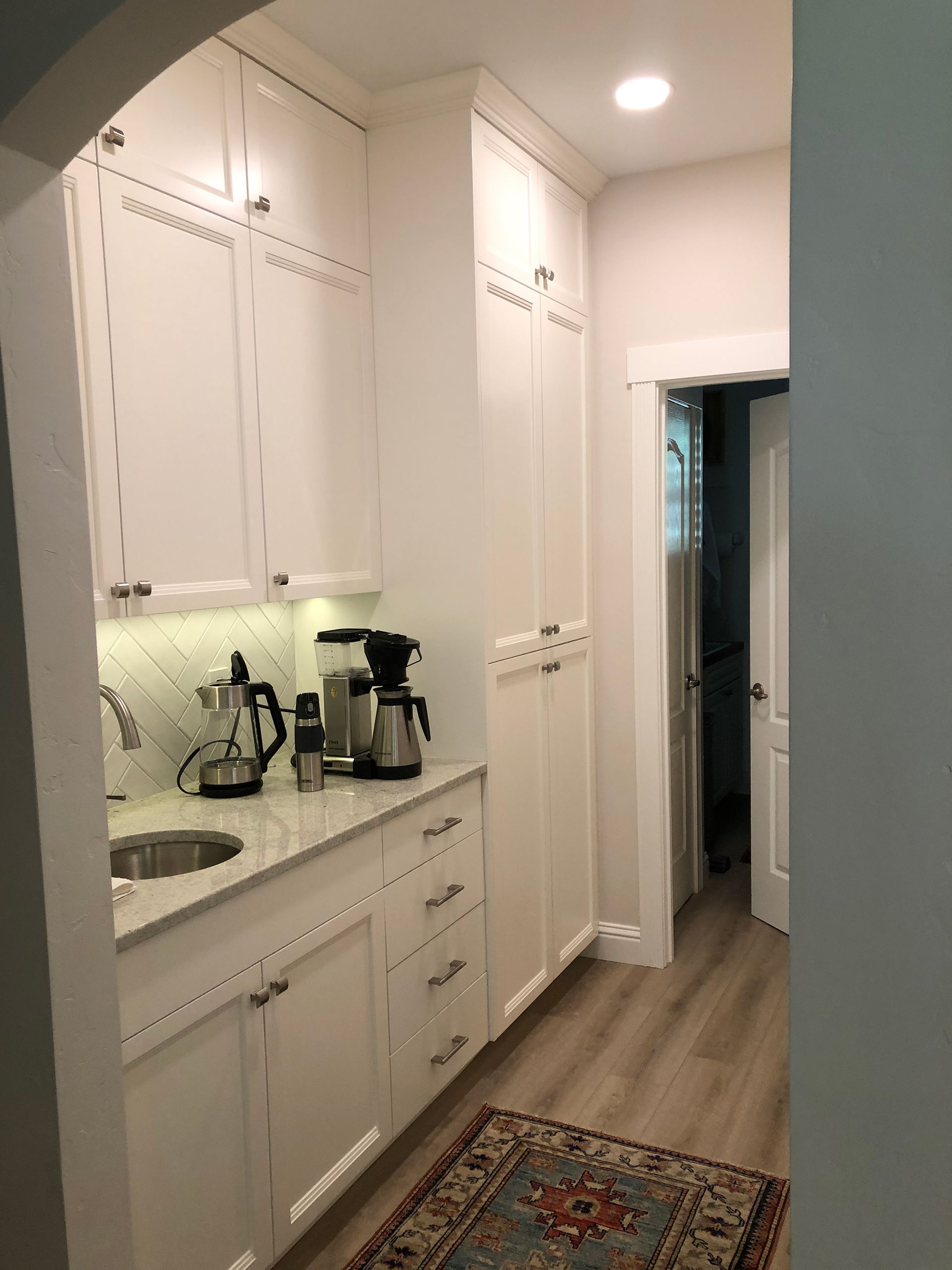 a kitchen with white cabinets , a sink , and a rug .