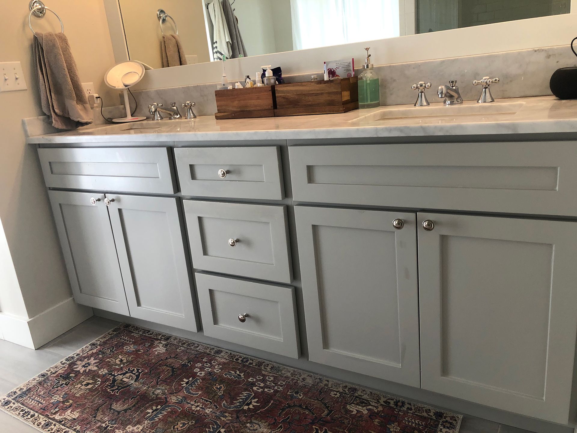 a bathroom with two sinks , a mirror and a rug .