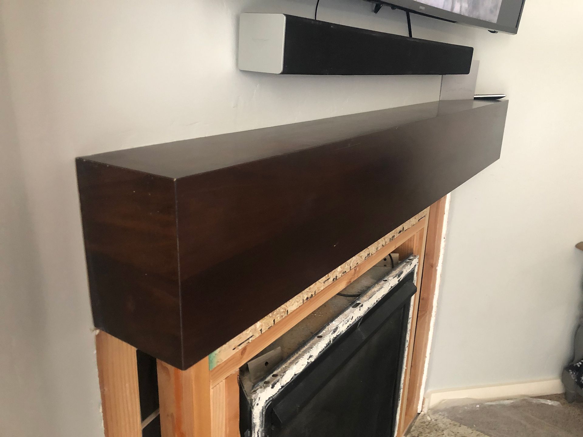 a fireplace with a wooden mantle and a television mounted on the wall .