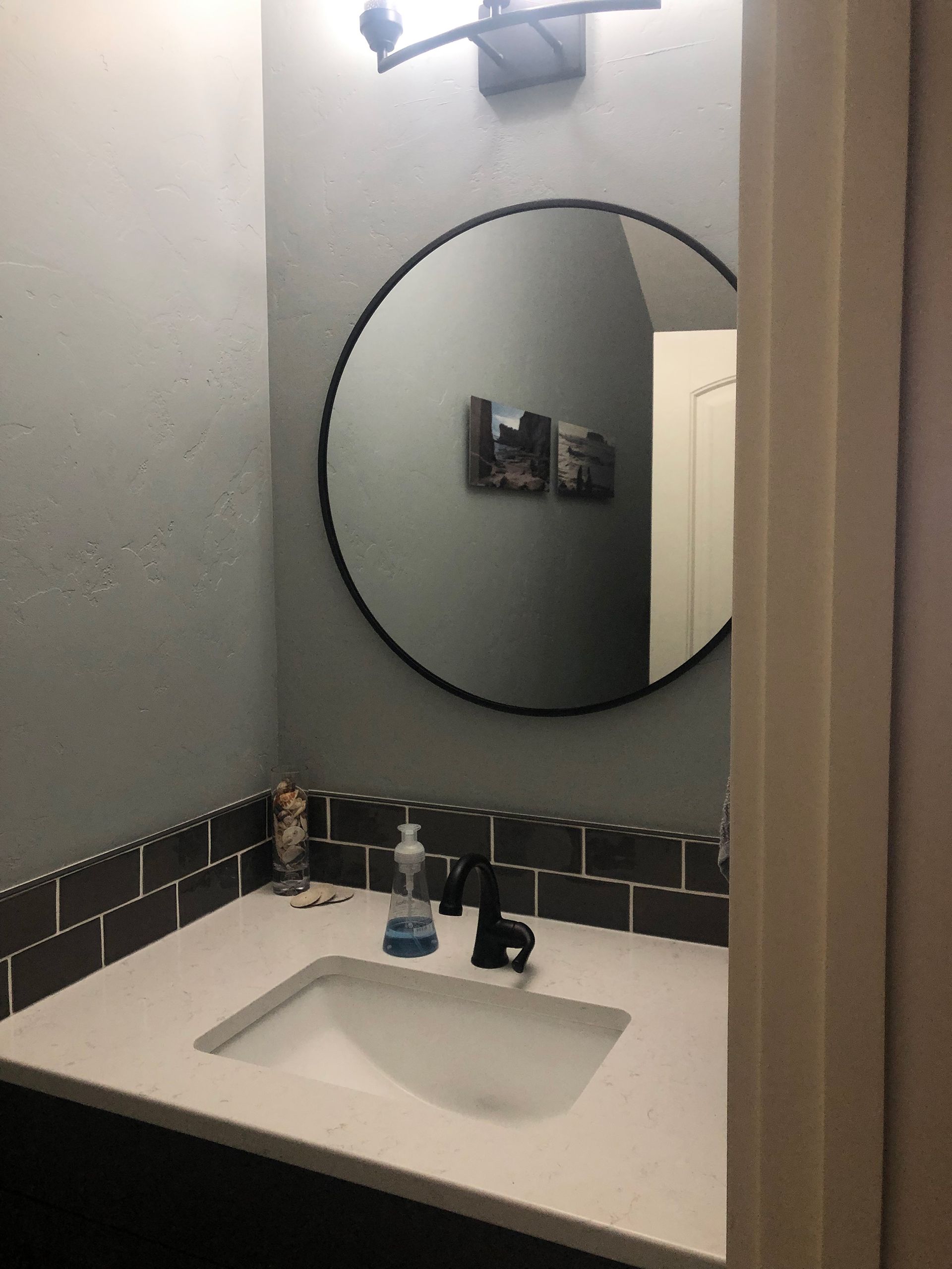 a bathroom with a sink and a round mirror