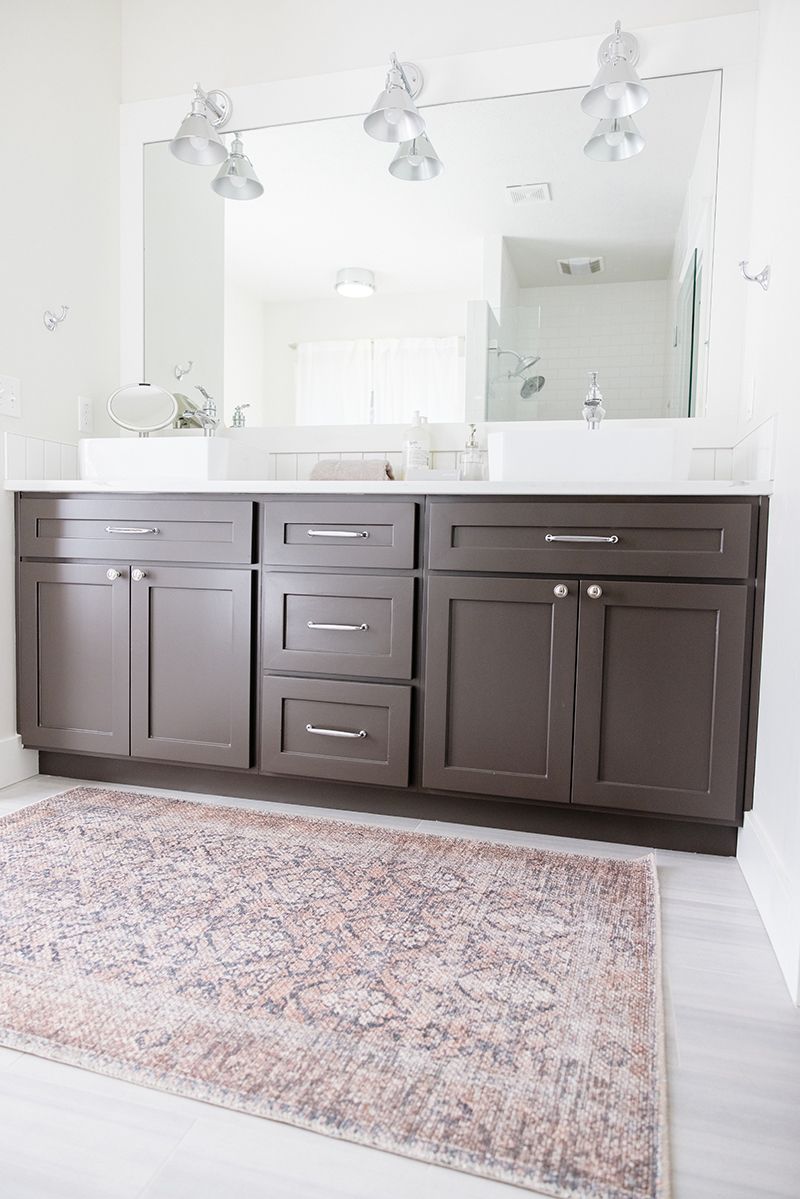 a bathroom with two sinks , a rug , and a large mirror .