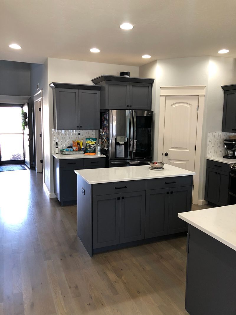 a kitchen with gray cabinets , stainless steel appliances , and a large island .