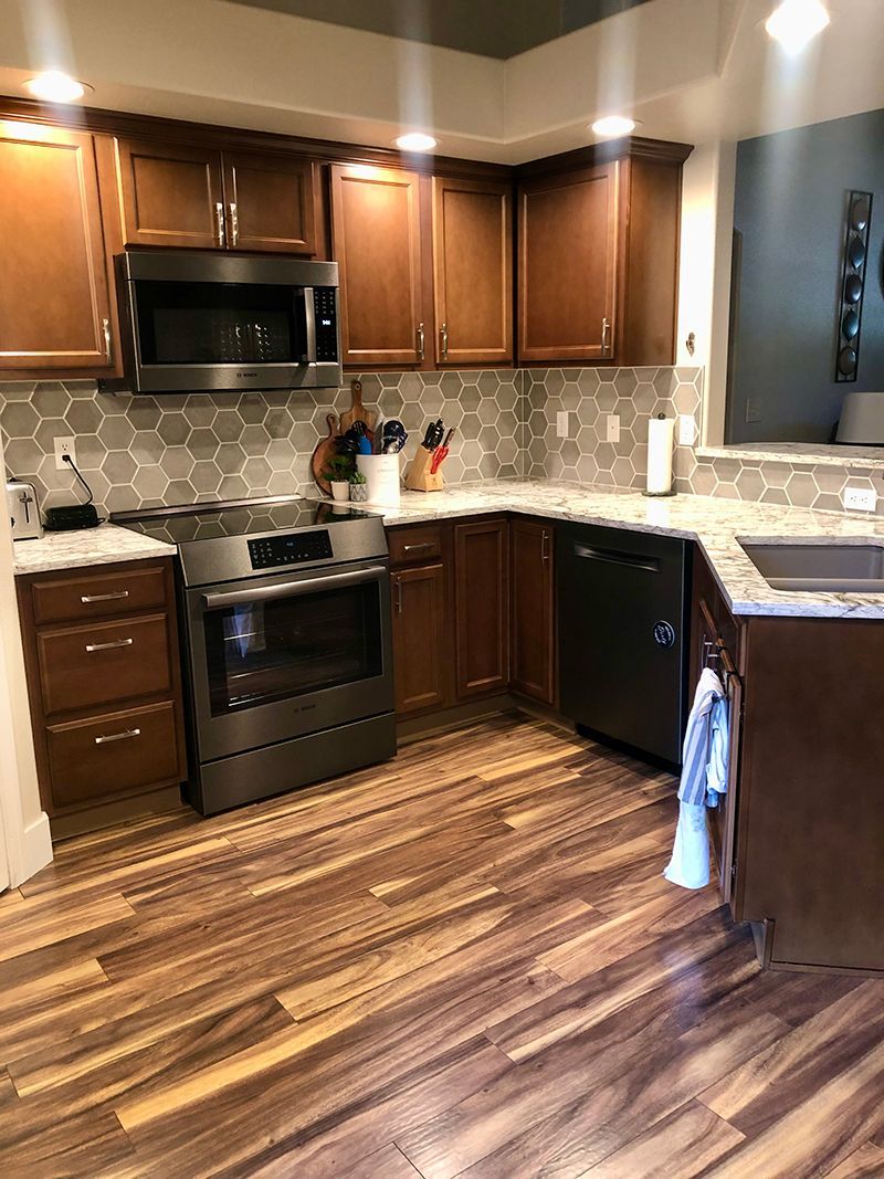 a kitchen with wooden cabinets , stainless steel appliances , a sink , and a stove .