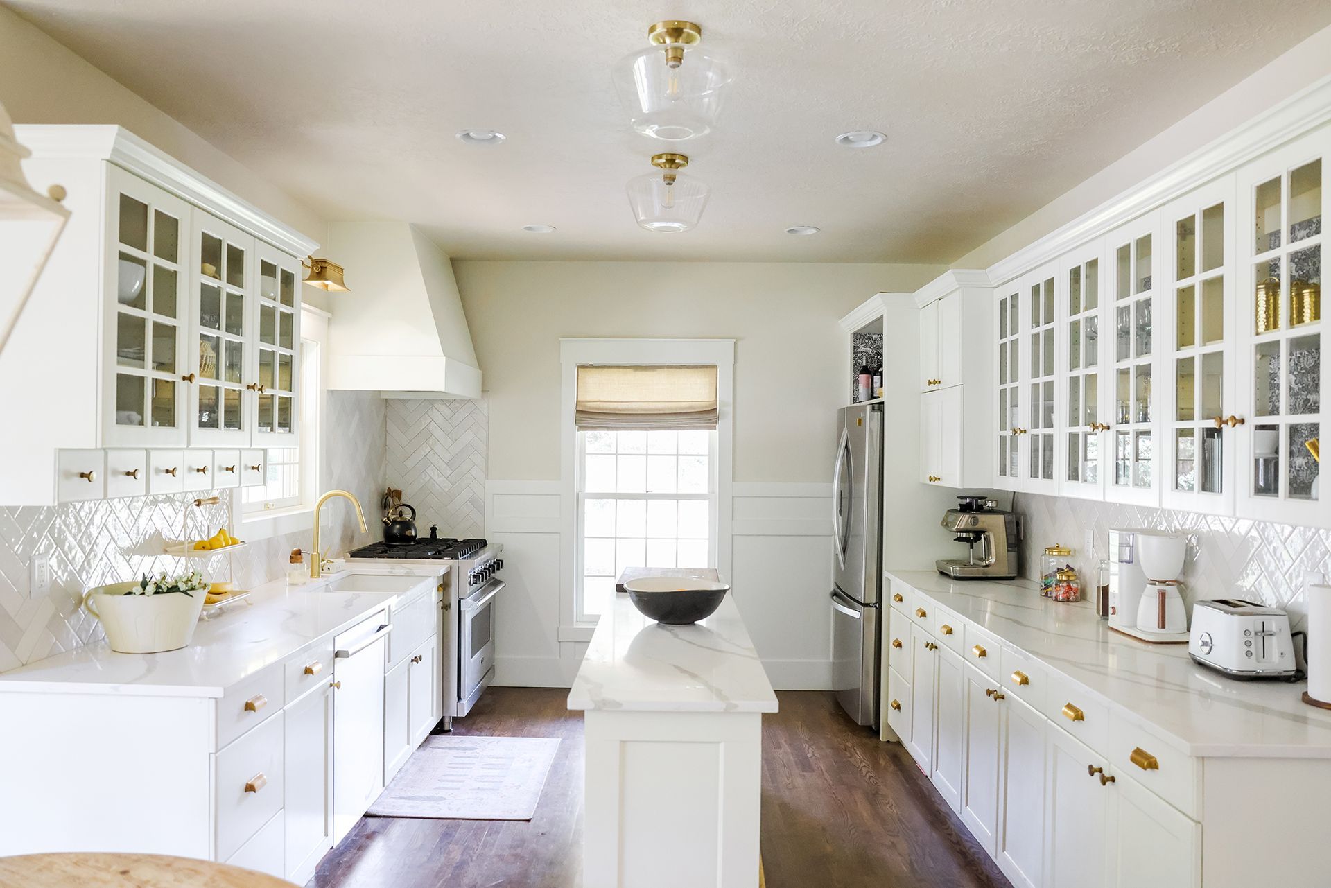 a kitchen with white cabinets , stainless steel appliances , and a large island .