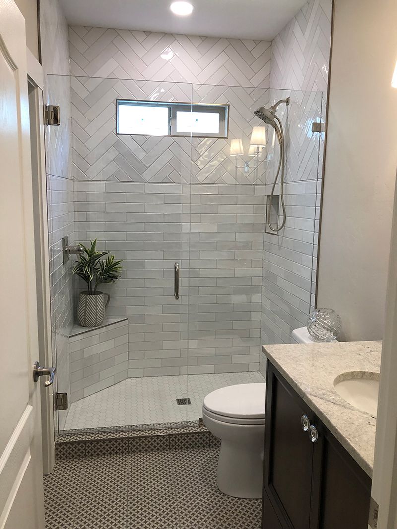 a bathroom with a toilet , sink and shower with a glass door .