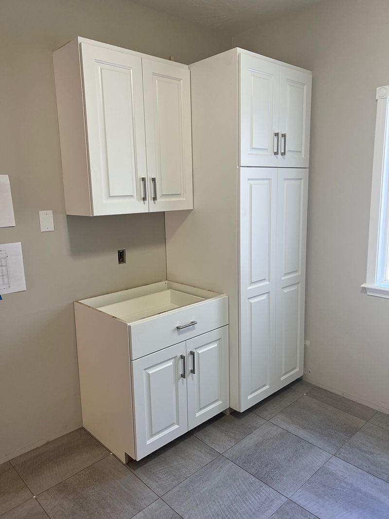 a kitchen with white cabinets , a sink , and a refrigerator .