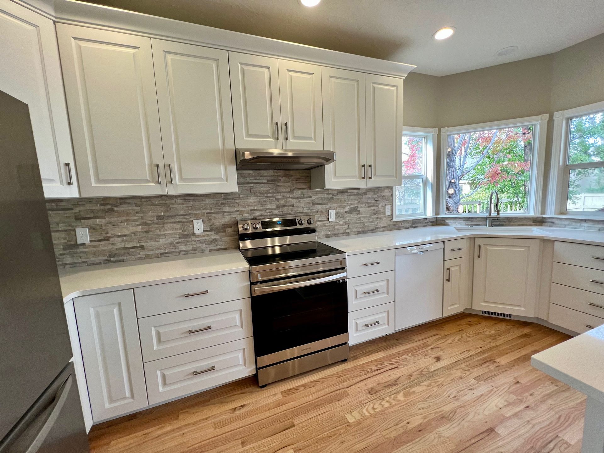 a kitchen with white cabinets , stainless steel appliances , and hardwood floors .