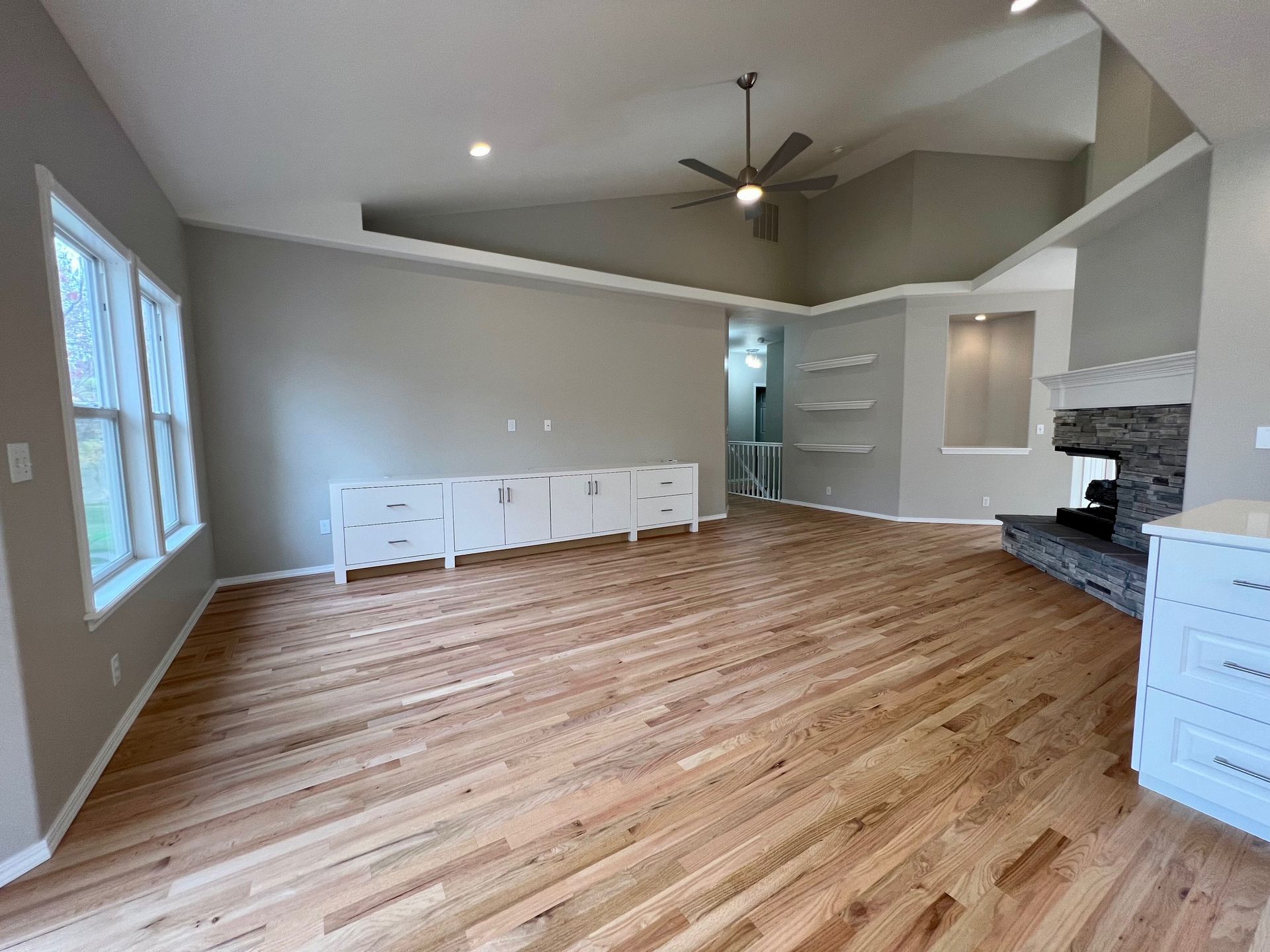 an empty living room with hardwood floors and a ceiling fan .