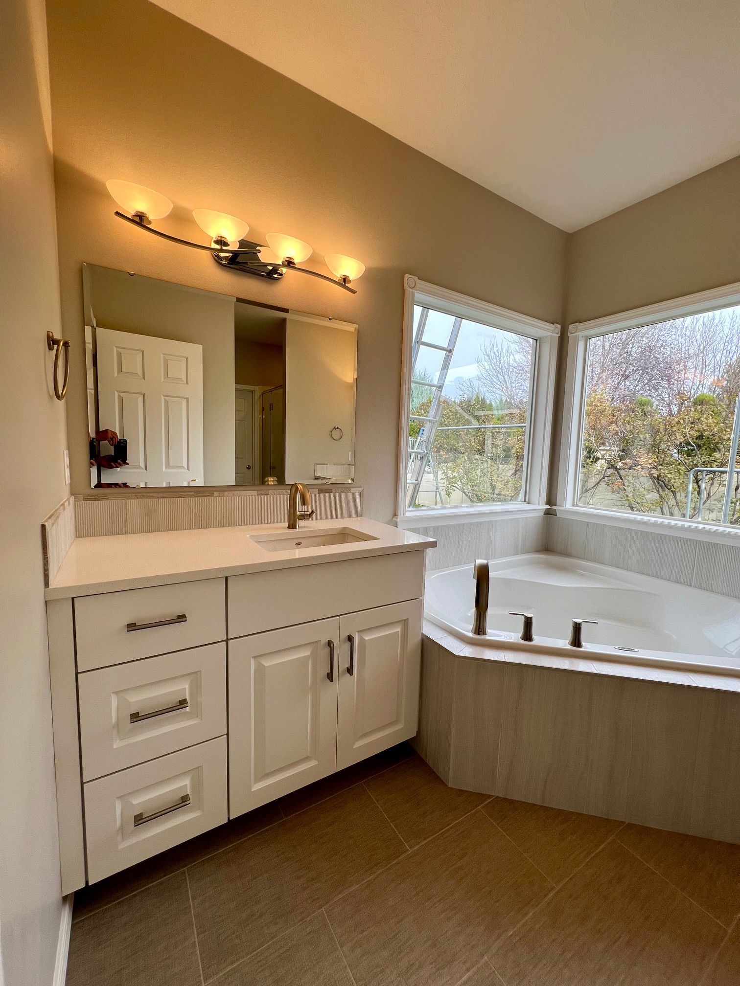 a bathroom with a tub , sink , mirror and window .