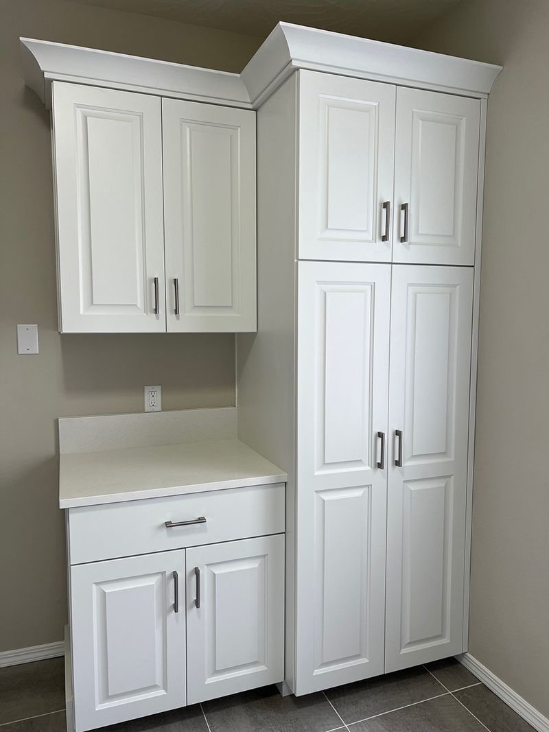a laundry room with white cabinets and a large cabinet .