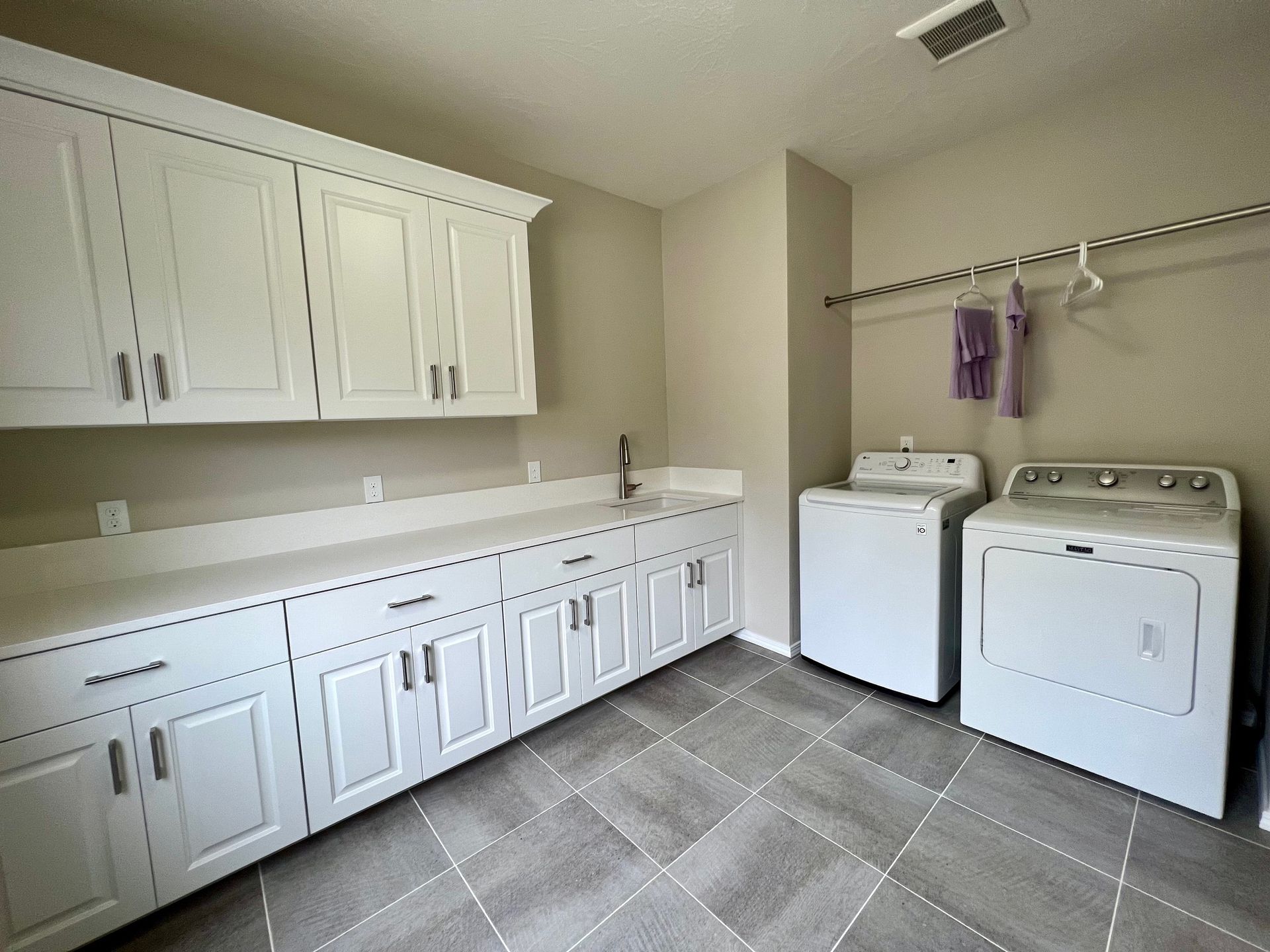 a laundry room with a washer and dryer and white cabinets