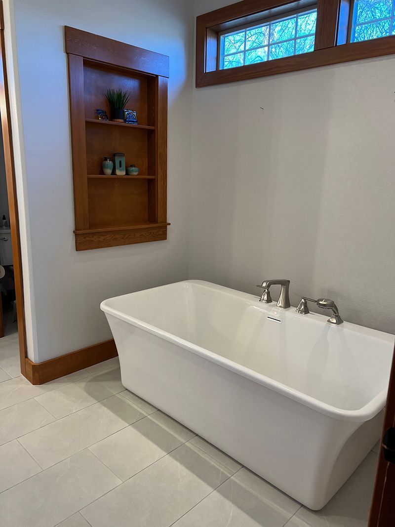 a bathroom with a large white bathtub and a window .