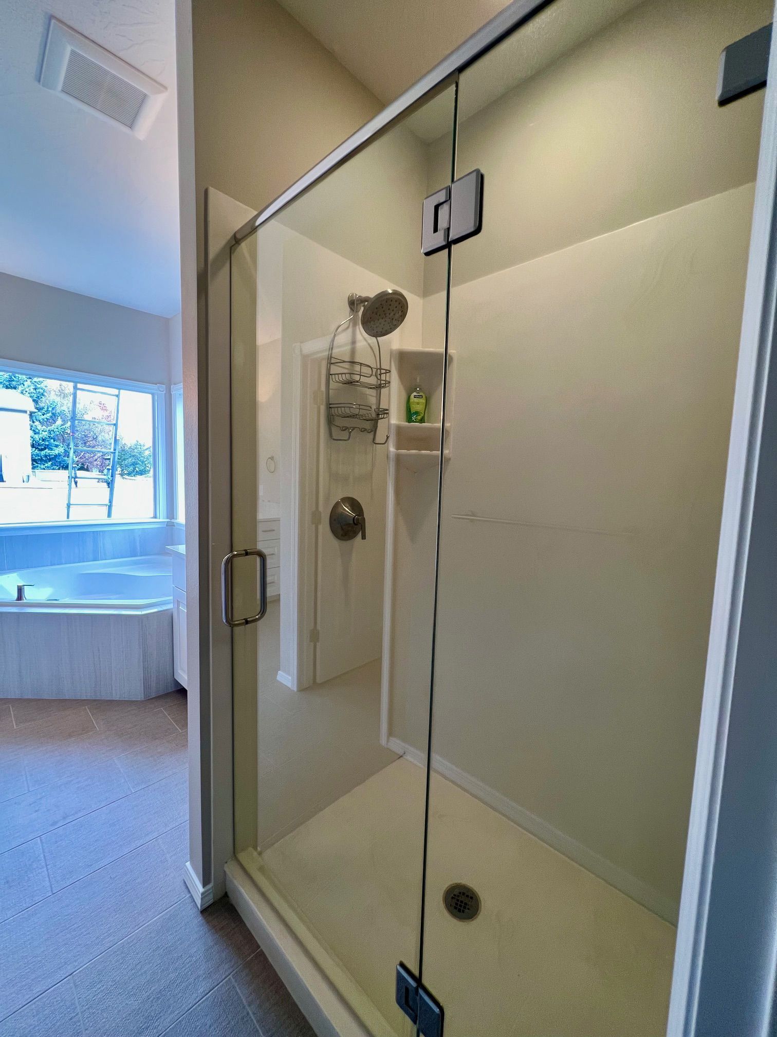 a bathroom with a walk in shower with a glass door .