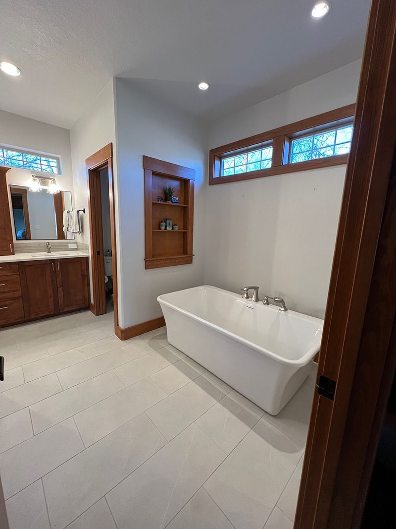 a bathroom with a bathtub , sink , mirror and window .